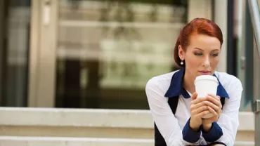 Woman sitting on outdoor steps holding a coffee cup.