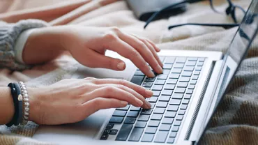 Hands typing on a laptop keyboard.