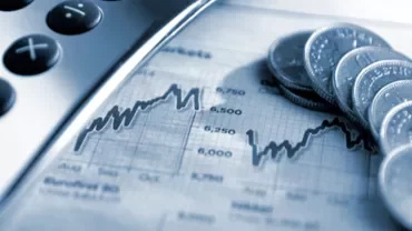 Close-up of coins, a calculator, and a financial graph.