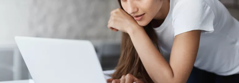 Woman in a white shirt using a laptop at a desk.