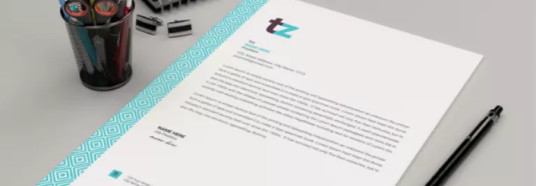 A modern letterhead on a desk with a pen holder and notebook.