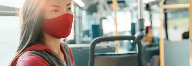 Woman wearing a red mask sitting on a bus