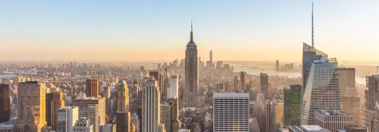 Skyline of New York City at sunset with the Empire State Building in view.
