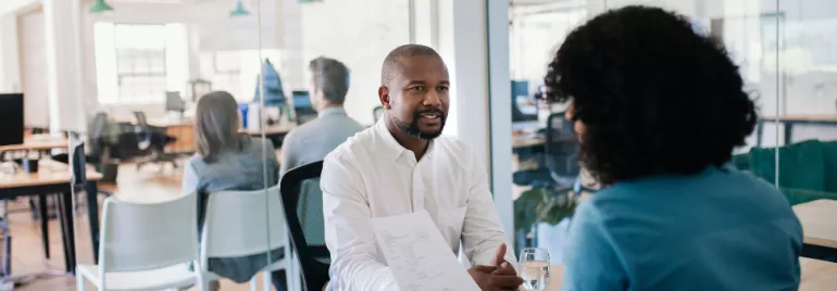 Two people having a conversation in a modern office setting.