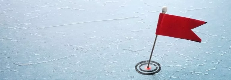 A red flag pin on a textured blue surface resembling ice.