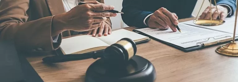 Two professionals discussing documents at a table with a gavel and scales.