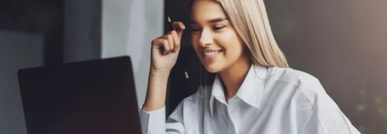 Woman smiling while looking at laptop screen.