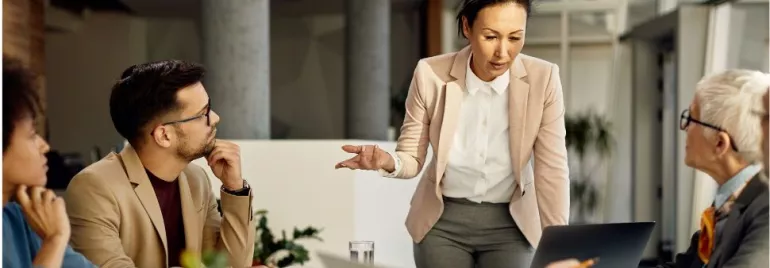 Businesswoman leading a meeting with colleagues around a table.