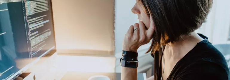 Woman working on code at a computer desk