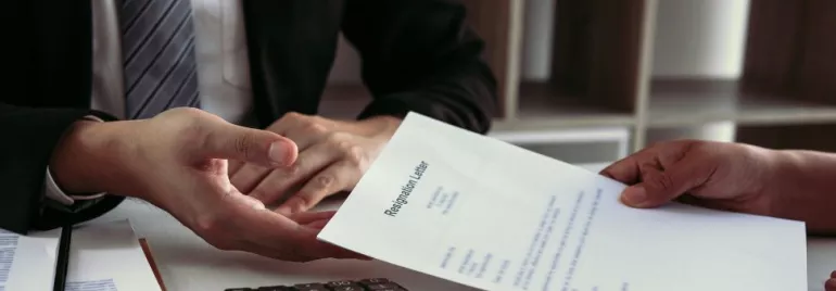 Person handing over a resignation letter across a desk