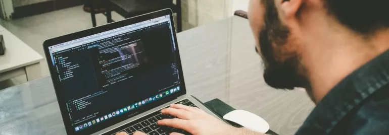 Person working on a laptop with code on the screen.
