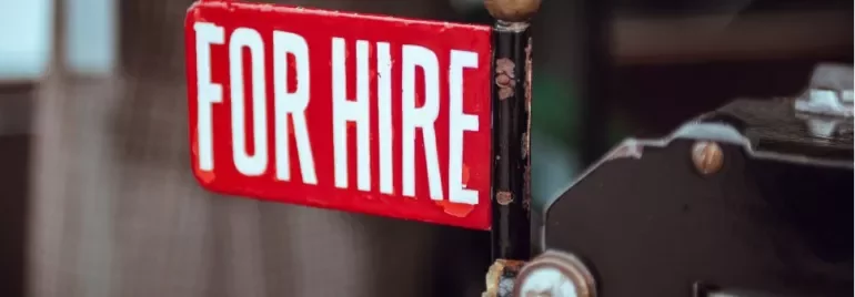 Close-up of a red 'For Hire' sign attached to a vintage taxi.