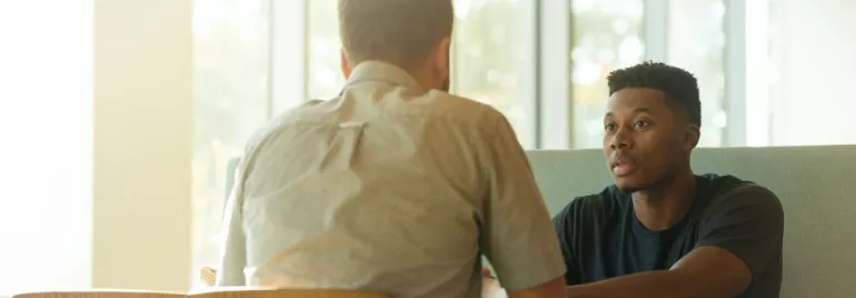 Two men sitting at a table engaged in a conversation.