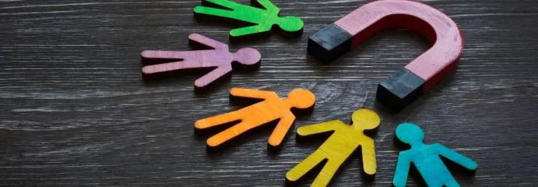 Colorful figures near a red magnet on a wooden table.