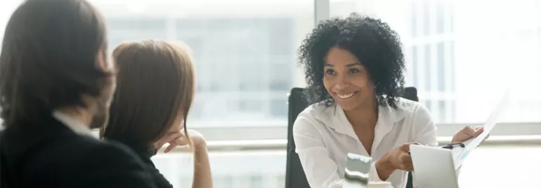 Woman smiling while holding papers in a meeting.