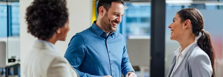 Three people having a cheerful conversation in an office setting.