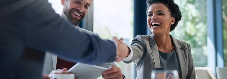 Smiling professionals shaking hands in a bright office
