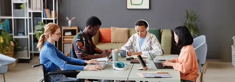 Diverse group of four people working together at a table in a modern office.