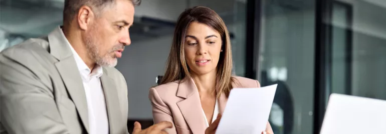 Two professionals discussing a document in a modern office.
