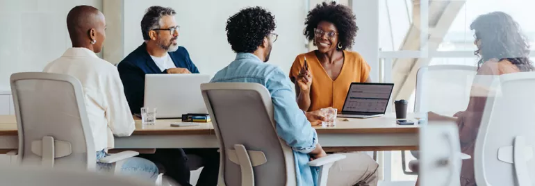 Group of diverse colleagues having a discussion around a conference table.