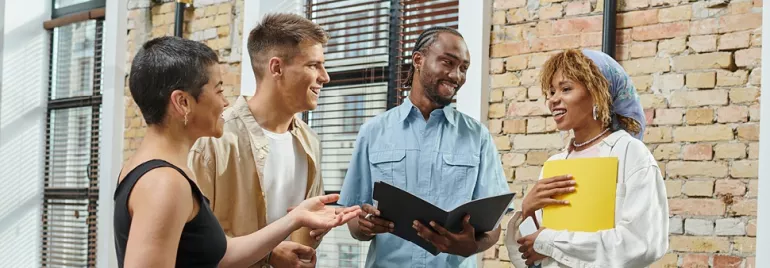 Diverse group of four people having a discussion in a bright office.
