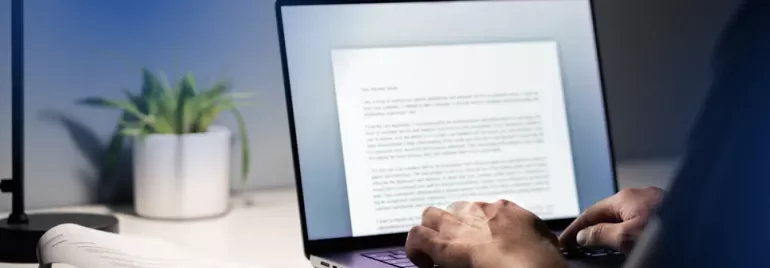 A man typing a resignation letter on a laptop