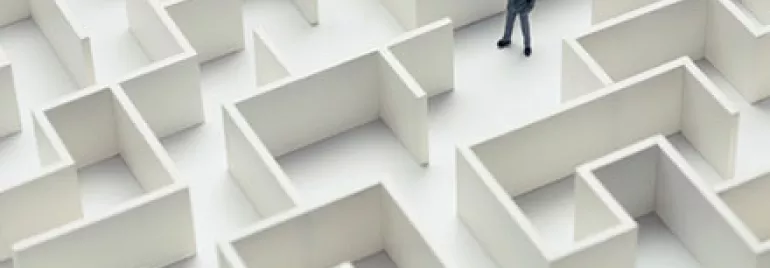 Businessman standing in a large maze, contemplating directions.