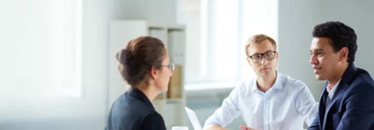 Three professionals having a meeting in a well-lit office room.