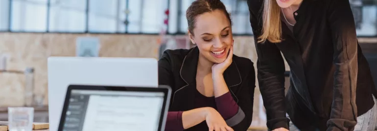 Two colleagues happily collaborating on a project in an office setting.