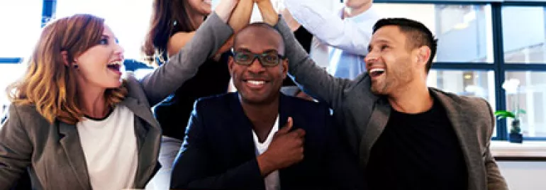 Group of colleagues celebrating with a high five in an office.