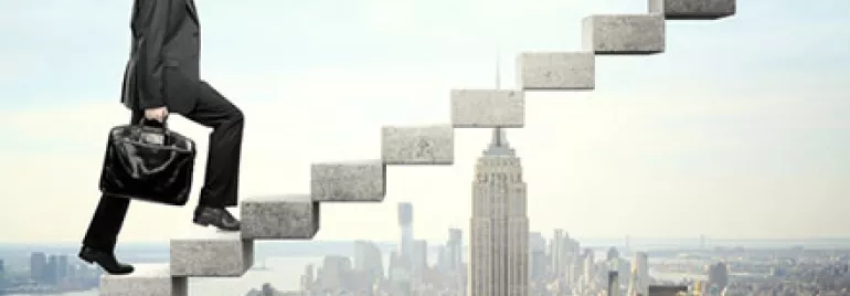 Businessman climbing floating stairs above city skyline.
