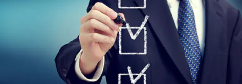 A man in a suit marking checkboxes on a transparent board.