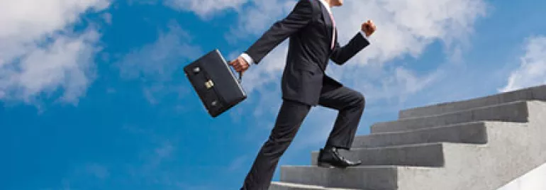 Man in a suit climbing stairs into the sky with a briefcase.