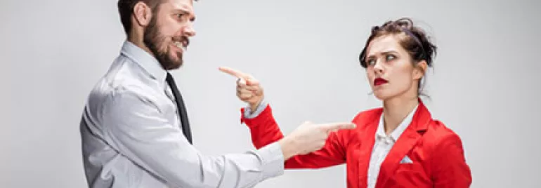 Man and woman in an argument pointing at each other.