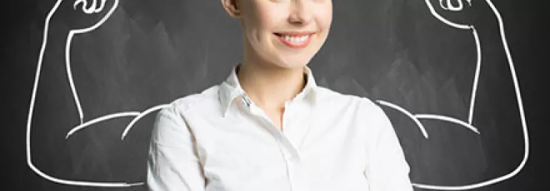 Smiling woman in white shirt with drawn strong arms on chalkboard background.