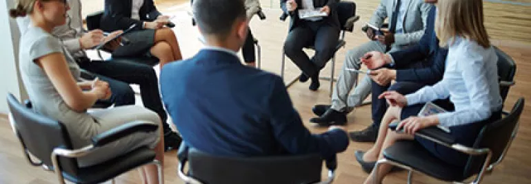 A group of business professionals in a meeting sitting in a circle.