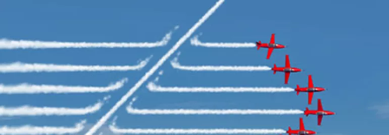 Nine red airplanes, one flying upward, leaving smoke trails in a clear blue sky.