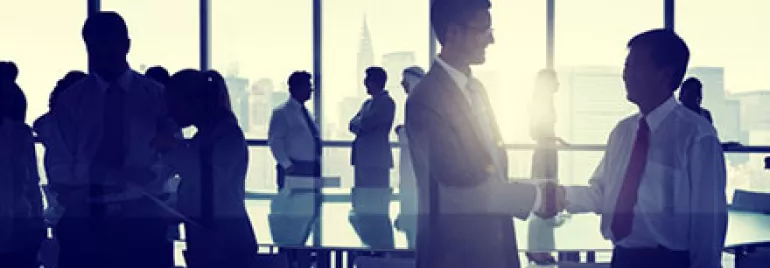 Silhouettes of business people interacting in a modern office setting.