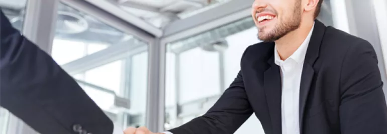 Smiling business professional shaking hands in an office setting.