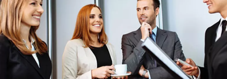 Group of business professionals smiling and engaging in a conversation.
