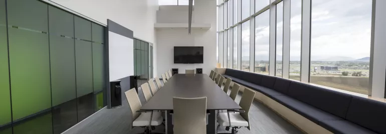 Modern conference room with a long table, chairs, and large windows.