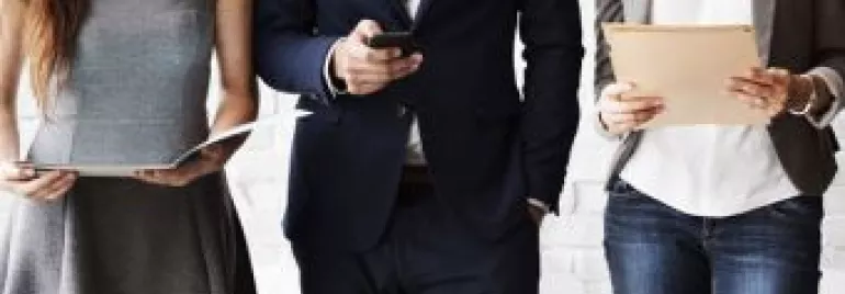 Three business professionals stand side by side holding documents and a phone.