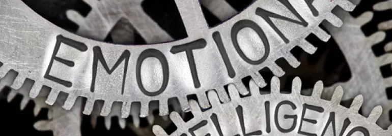 Close-up of metal cogs with 'Emotional Intelligence' engraved on them.