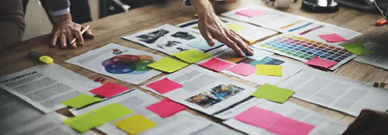 Team collaborating over documents and colorful sticky notes on a wooden table.