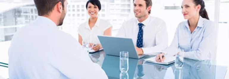 Group interview in modern office with four professionals discussing at a table.
