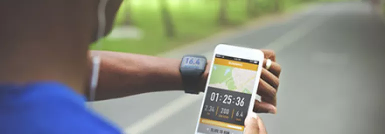 Person running with fitness tracker and smartphone, tracking activity data.