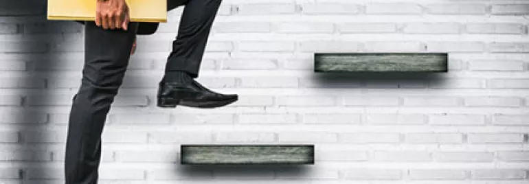 Businessman ascending steps with briefcase against a brick wall.
