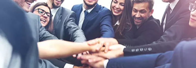 Group of business professionals stacking hands in teamwork.
