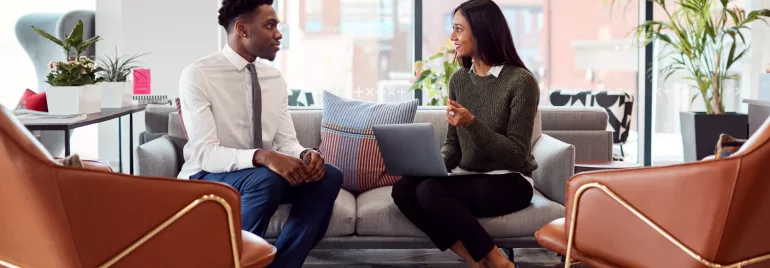 Two people having a discussion in a modern office lounge.