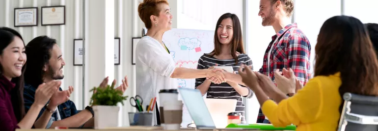 Group of coworkers celebrating a successful meeting with a handshake.